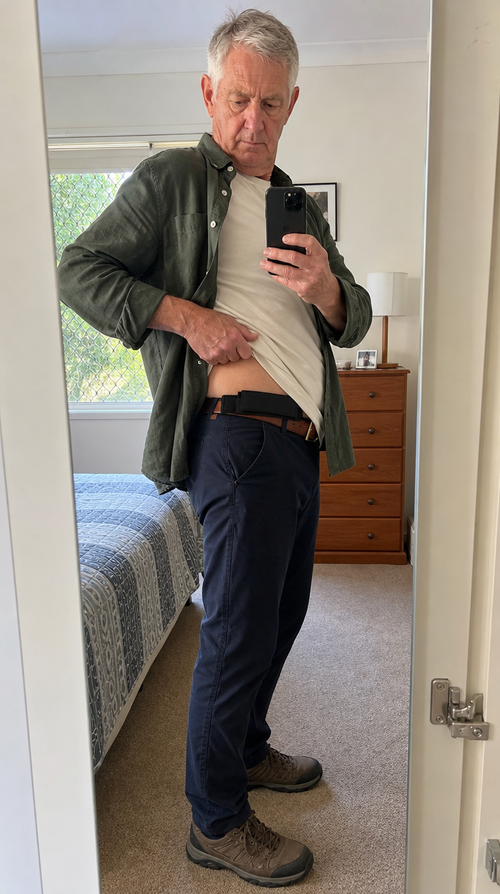 Man in a green shirt showing the hidden money belt pouch worn flat at his waistband under his shirt